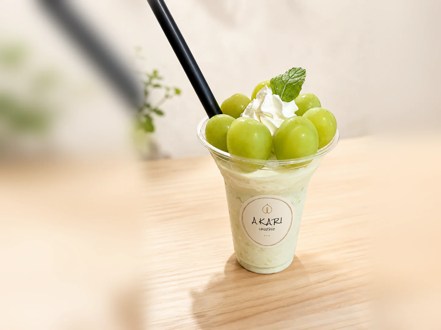AKARI のロゴ入りカップに注いだシャインマスカットのスムージー。生クリームとミントを添えて